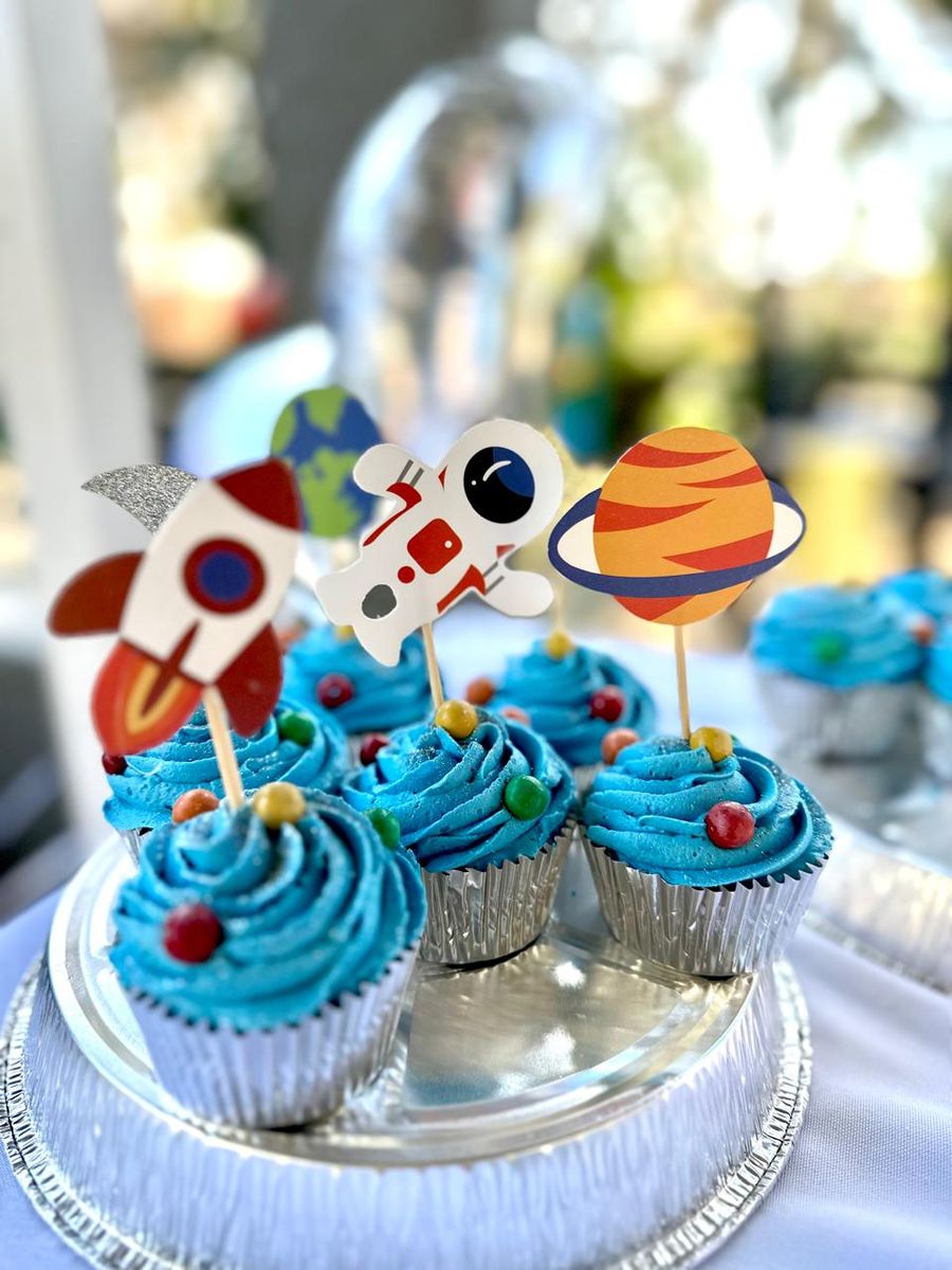 Blue-iced cupcakes with rocket, astronaut and planet toppers